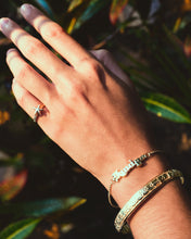 Load image into Gallery viewer, A woman&#39;s hand adorned with Hawaiian bracelets and ring
