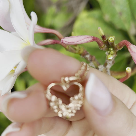 Woman holding Hawaiian Heart Pendant engraved with three plumeria flowers 